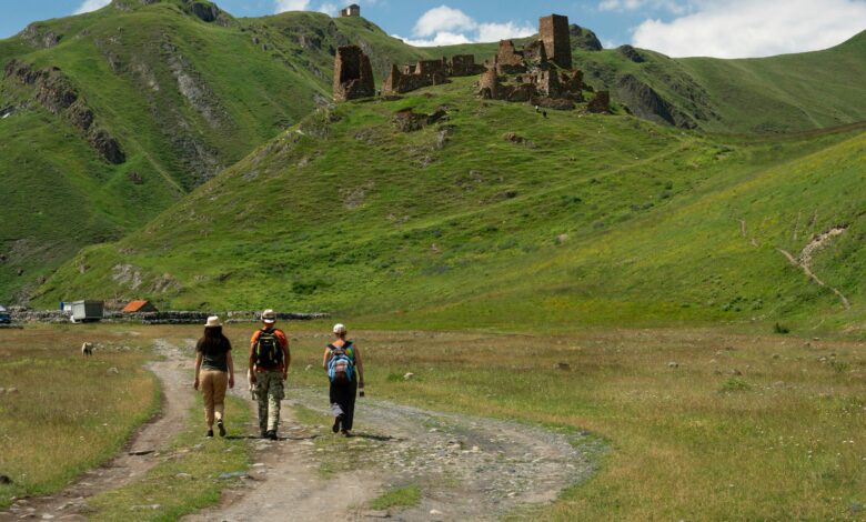 تكلفة السفر من دول الخليج إلى جورجيا 2026 الميزانية بالتفصيل | مدونتي السياحية منظر طبيعي في جورجيا يظهر مسافرين في رحلة مشي وسط الجبال الخضراء وآثار تاريخية، وجهة سياحية مميزة للمسافرين من دول الخليج